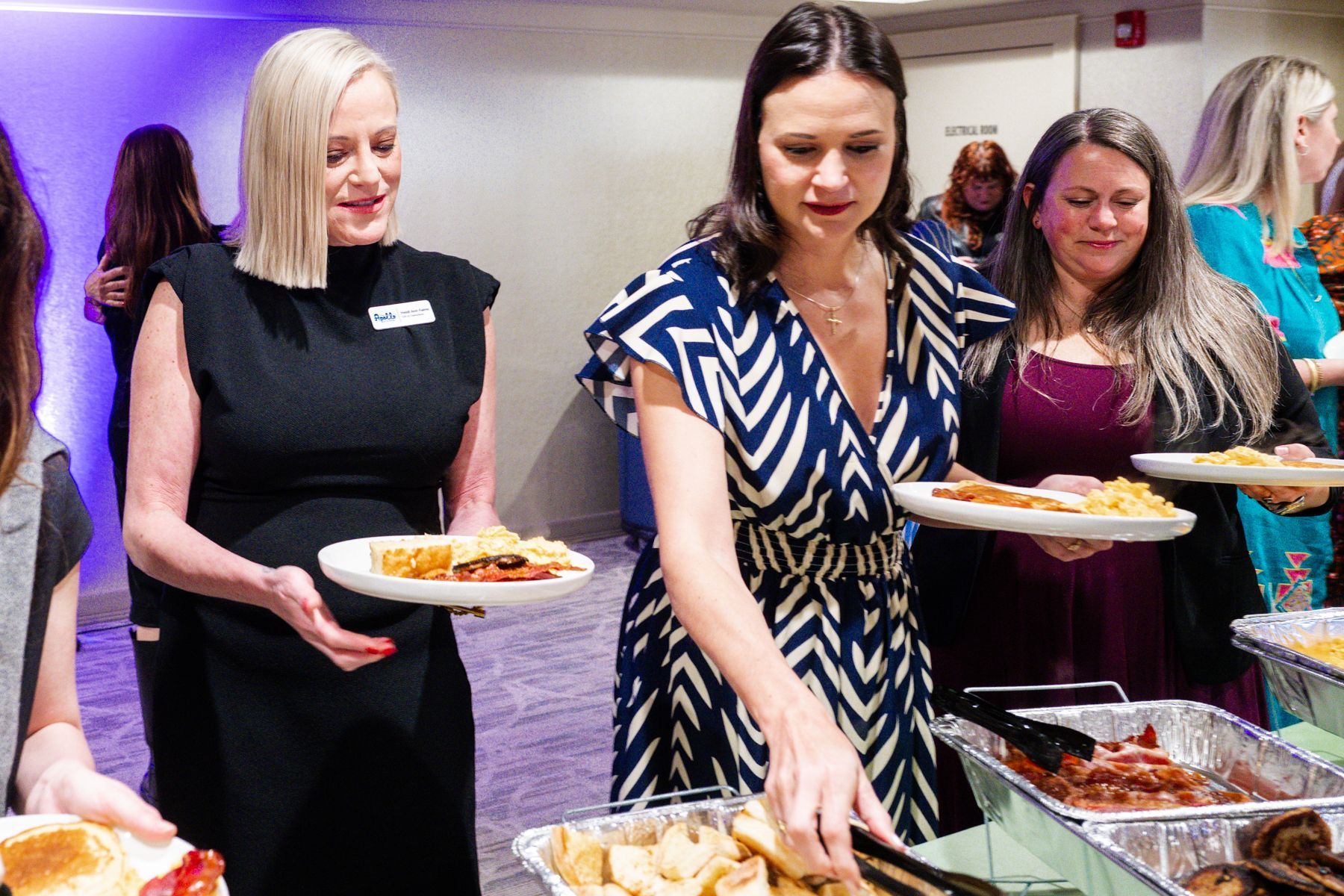 People at an event serving themselves food from a buffet.