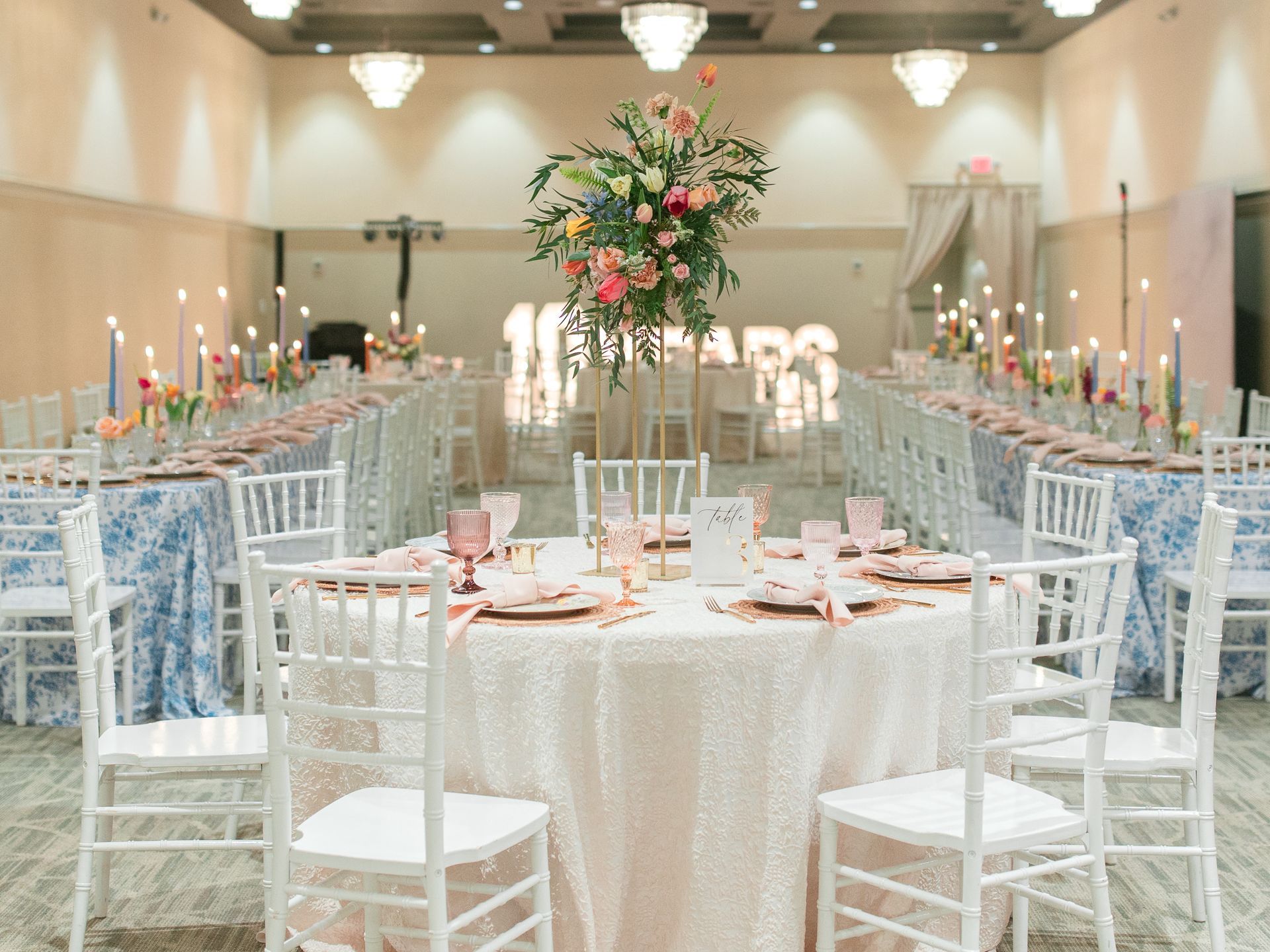Wedding reception with long tables, floral centerpieces, candles, and a sparkling tablecloth.