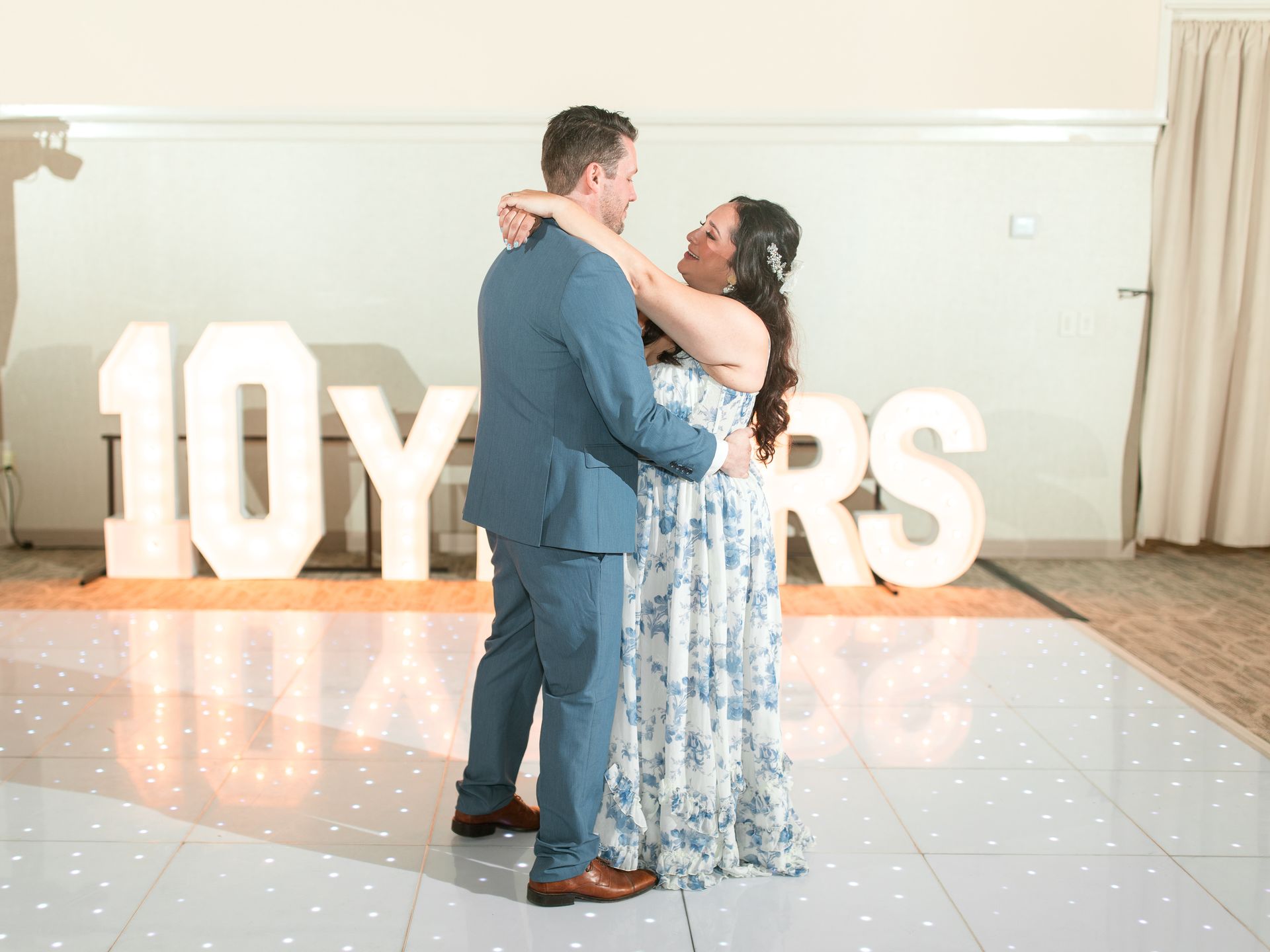 Bartender pouring champagne, smiling. Bar with patrons, flowers, and champagne bottles.