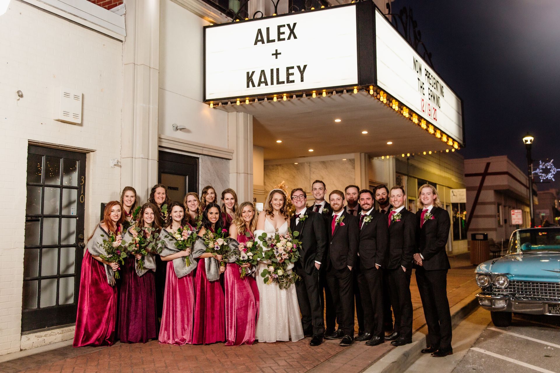 Wedding party poses in front of a theater marquee reading 