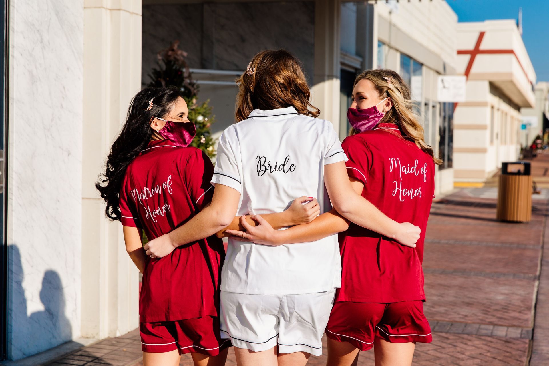 Three women in pajamas embrace outdoors; 