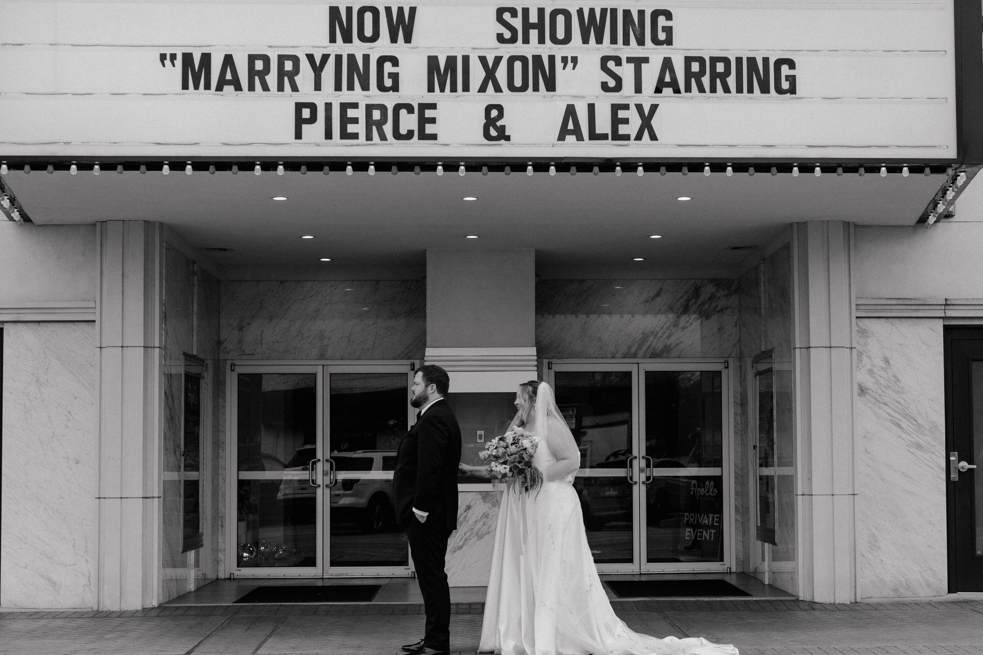 Wedding couple stands in front of a movie theater marquee reading 