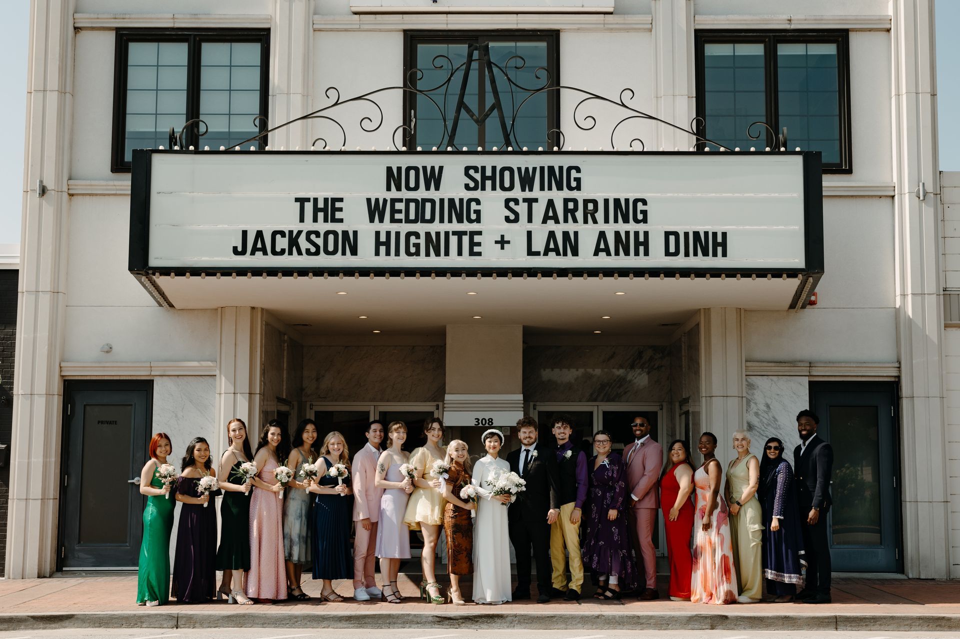 Group of people in wedding attire outside a theater marquee reading 