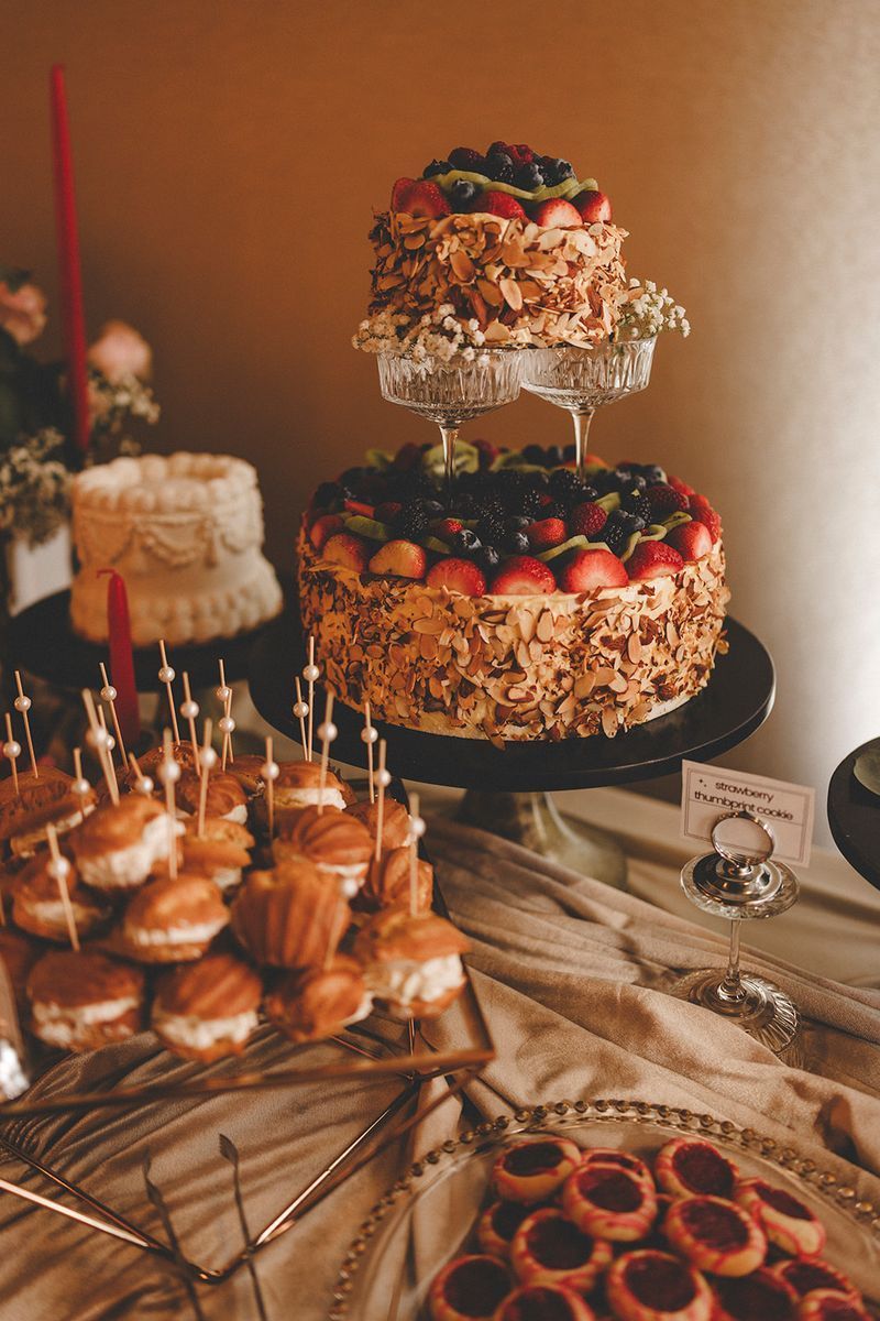 Dessert table with tiered cakes, pastries, and garnishes. Neutral color palette, elegant setting.