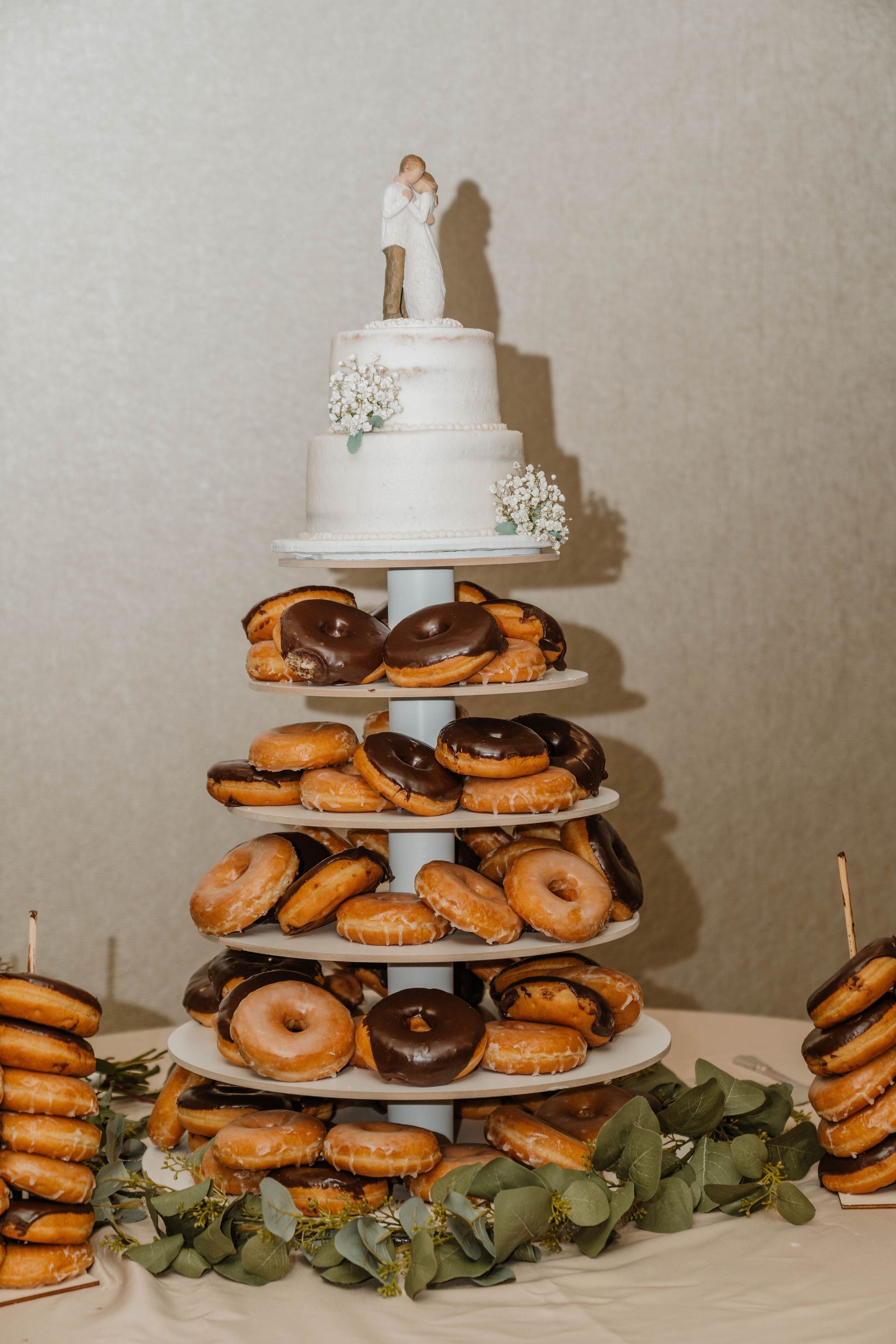 Wedding cake with tiers of donuts and a small cake topper.