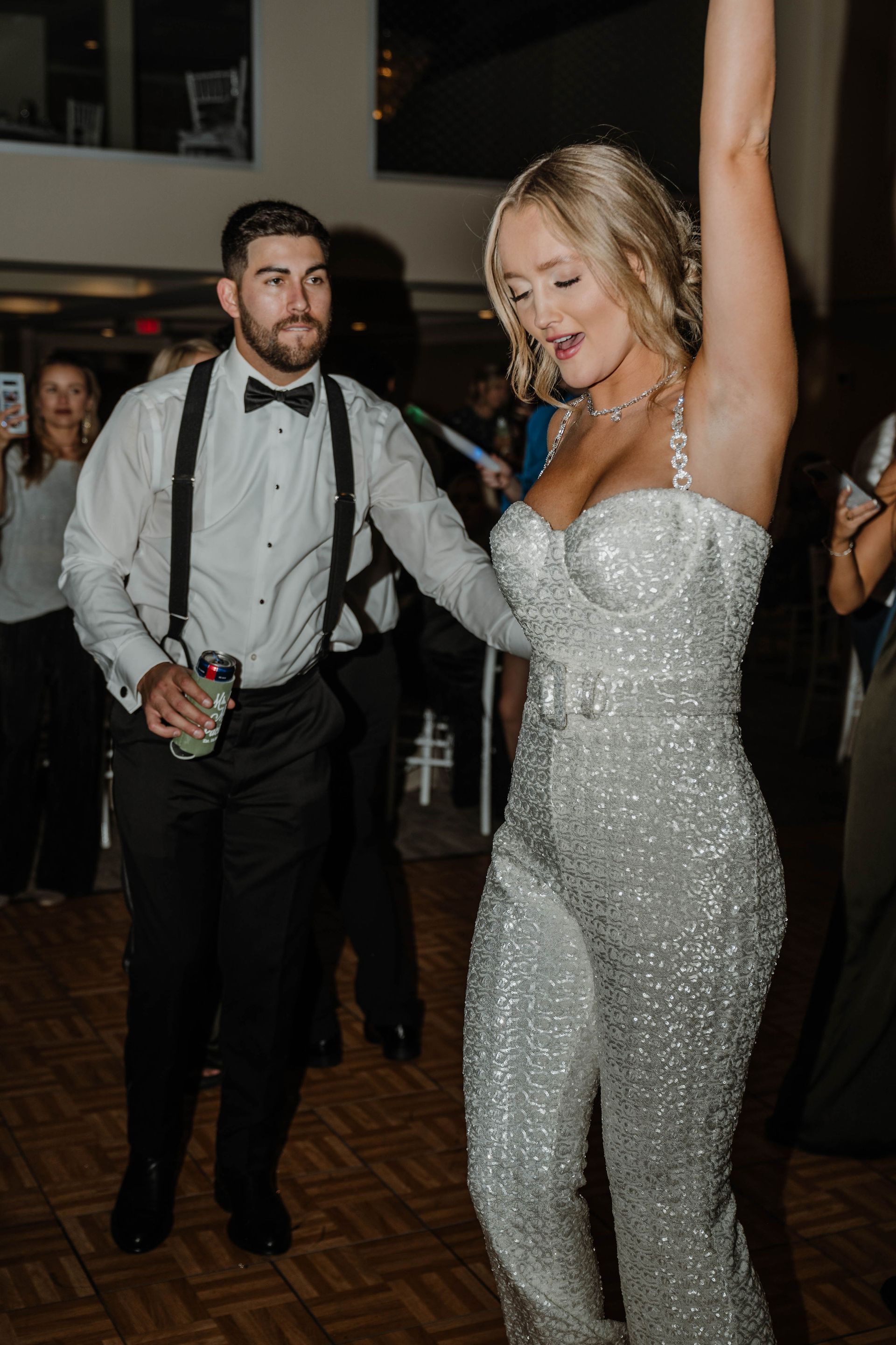 Man dancing with woman in sparkly jumpsuit at an event.