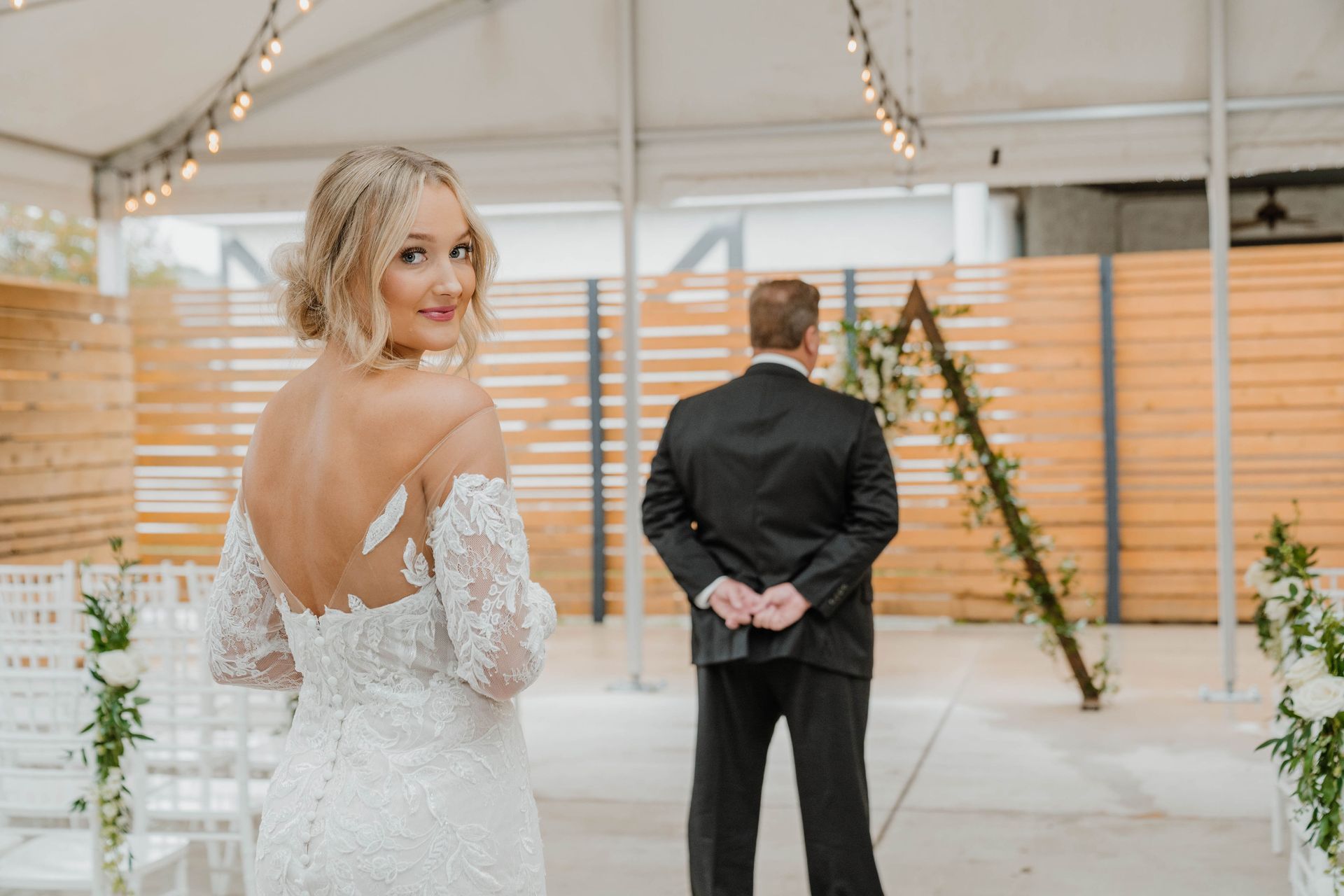 Bride in wedding dress looking over shoulder at groom before ceremony.