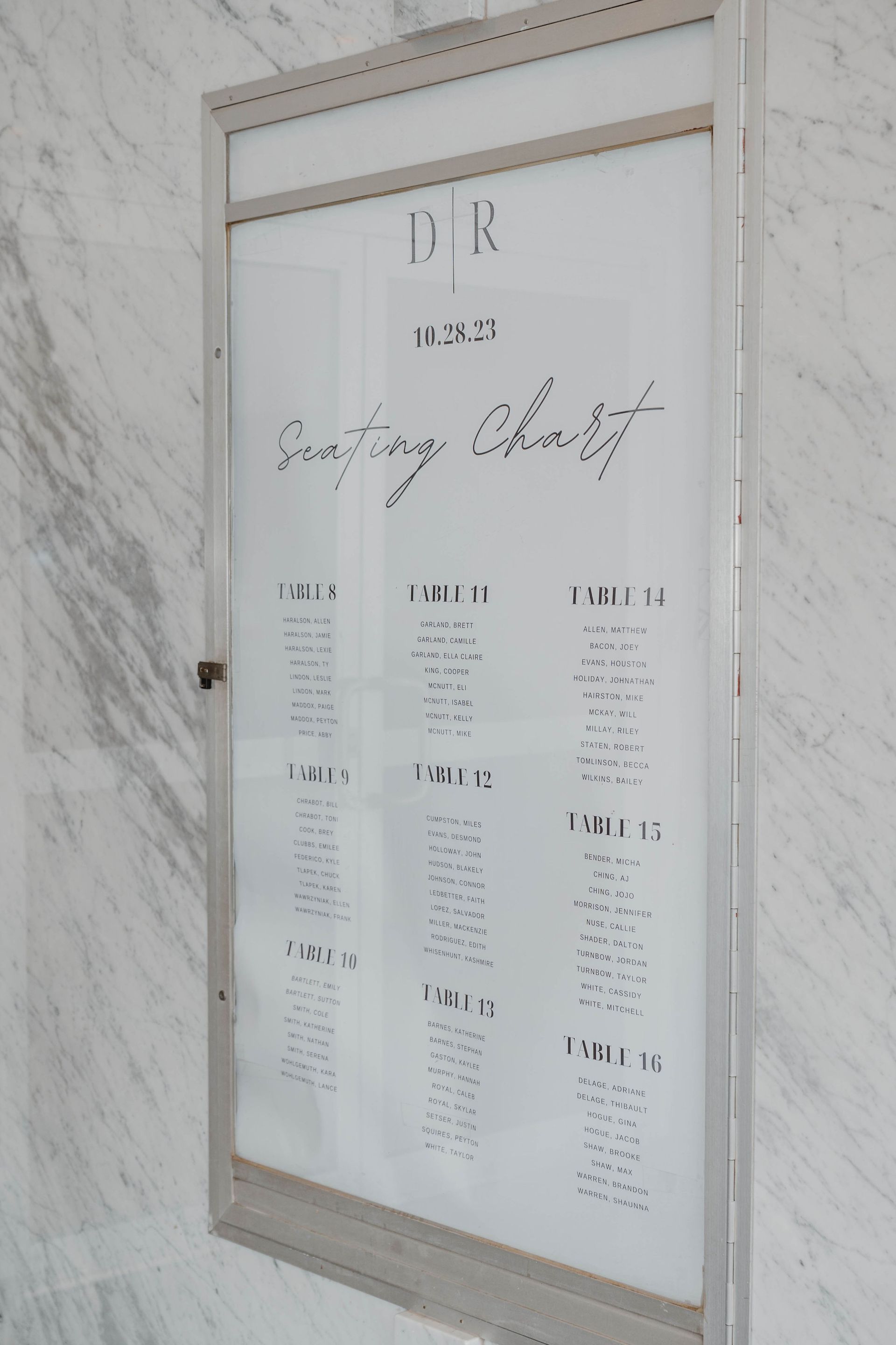 Signboard with list of names, likely for an event, against a marble wall.