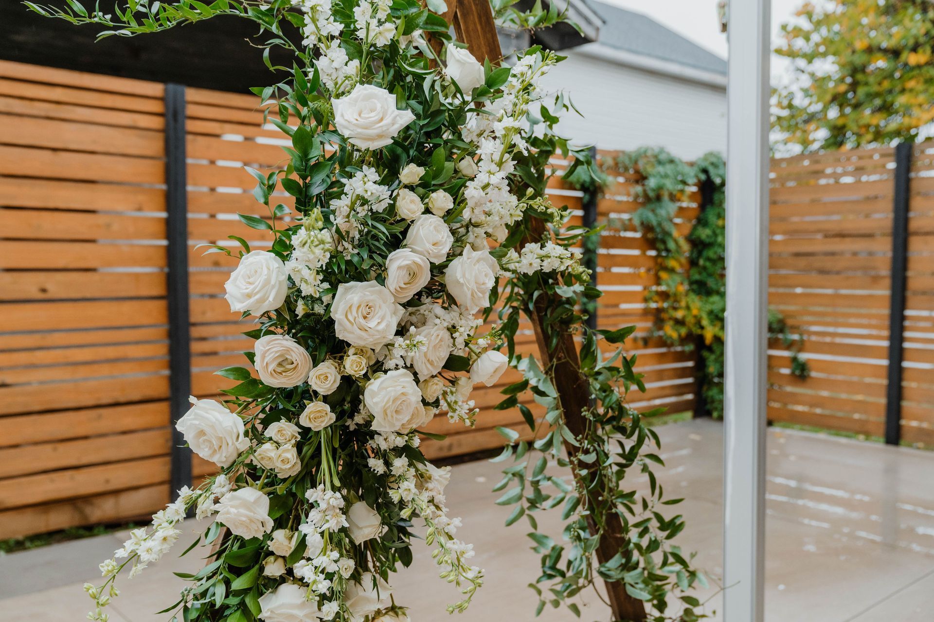 Three-tiered blue cake with ribbon detail on a table with fruit, and another white cake in the background.