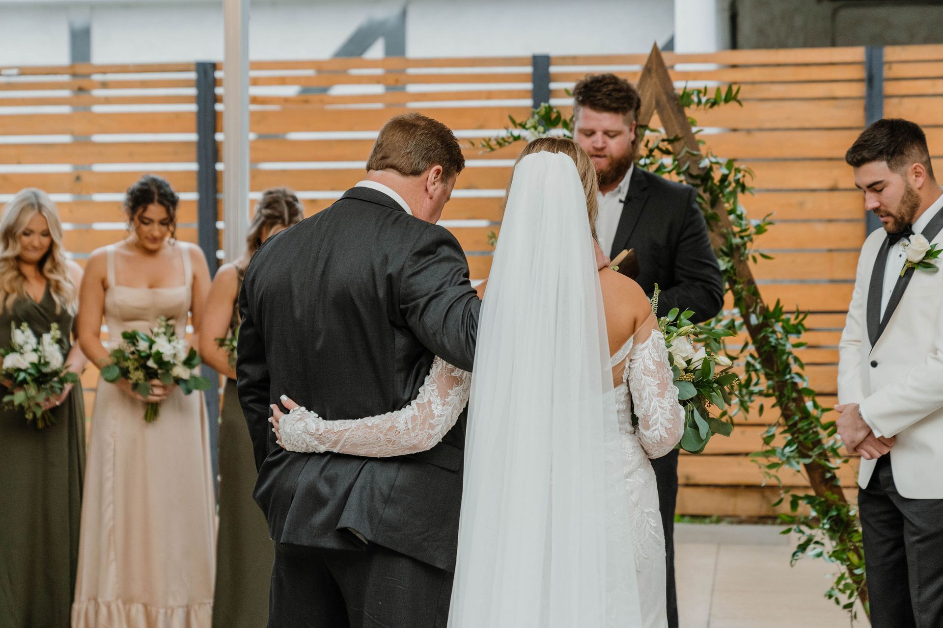 Wedding ceremony: Father walks bride down the aisle, officiant stands nearby.