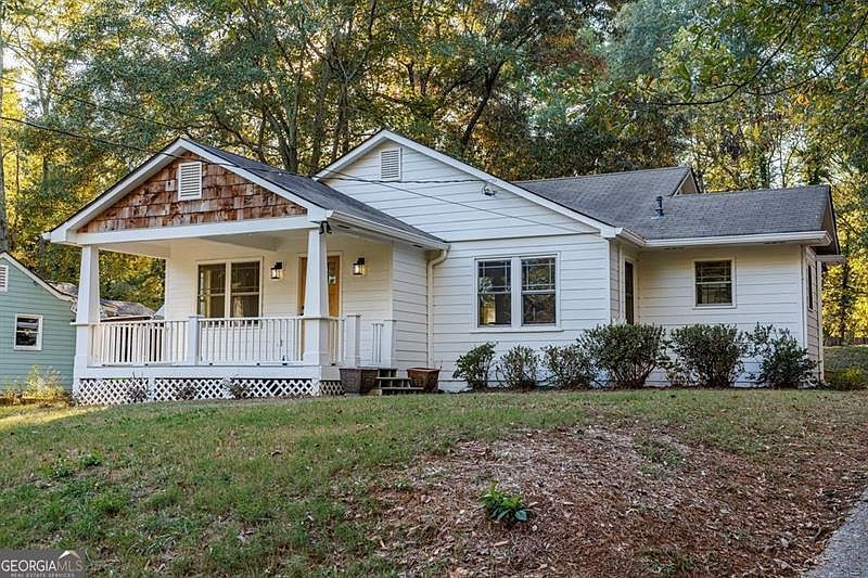 A white house with a wooden garage door and a concrete walkway leading to it.