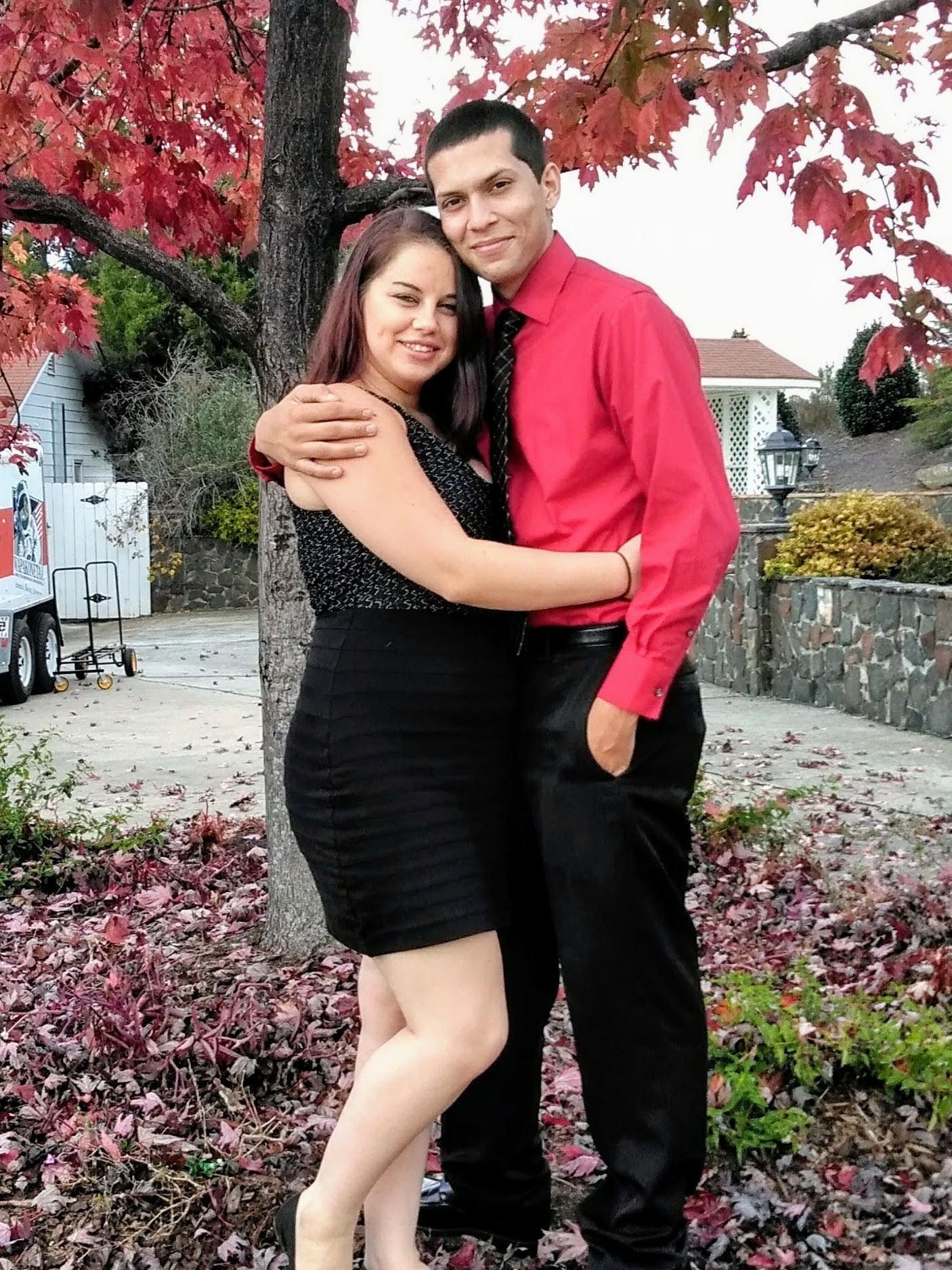 A man in a red shirt is hugging a woman in a black dress