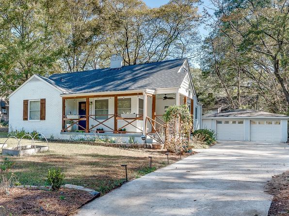 A large house with a driveway leading to it is surrounded by trees.