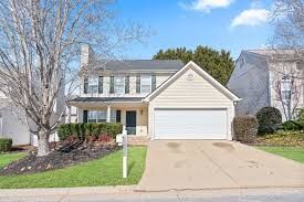 The back of a white house with a large lawn in front of it.