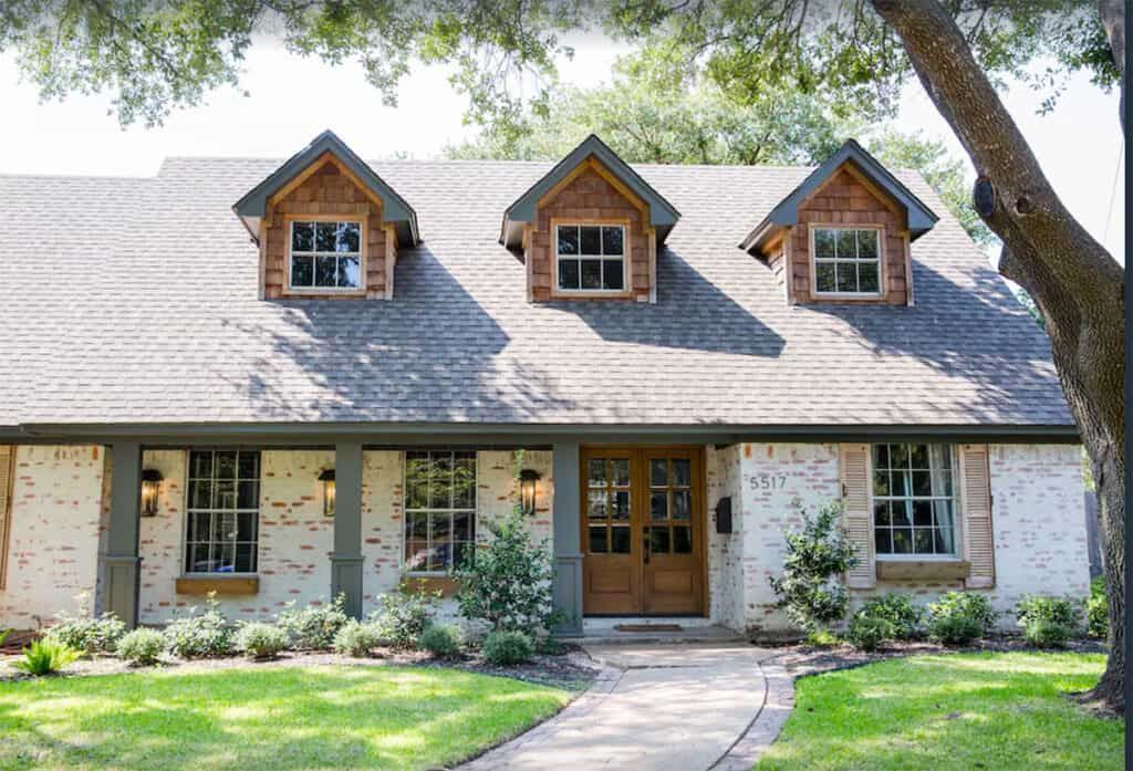 A large white house with a black garage door is for sale.