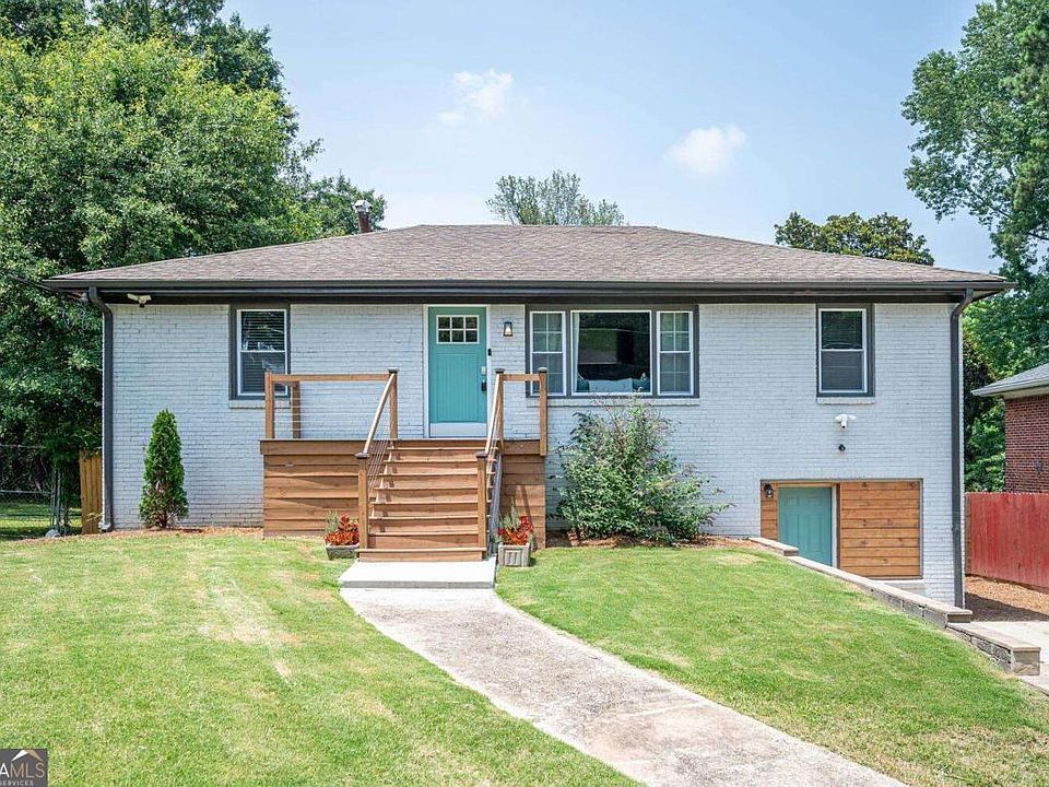 A large white house with a brown roof and a brick walkway leading to it.