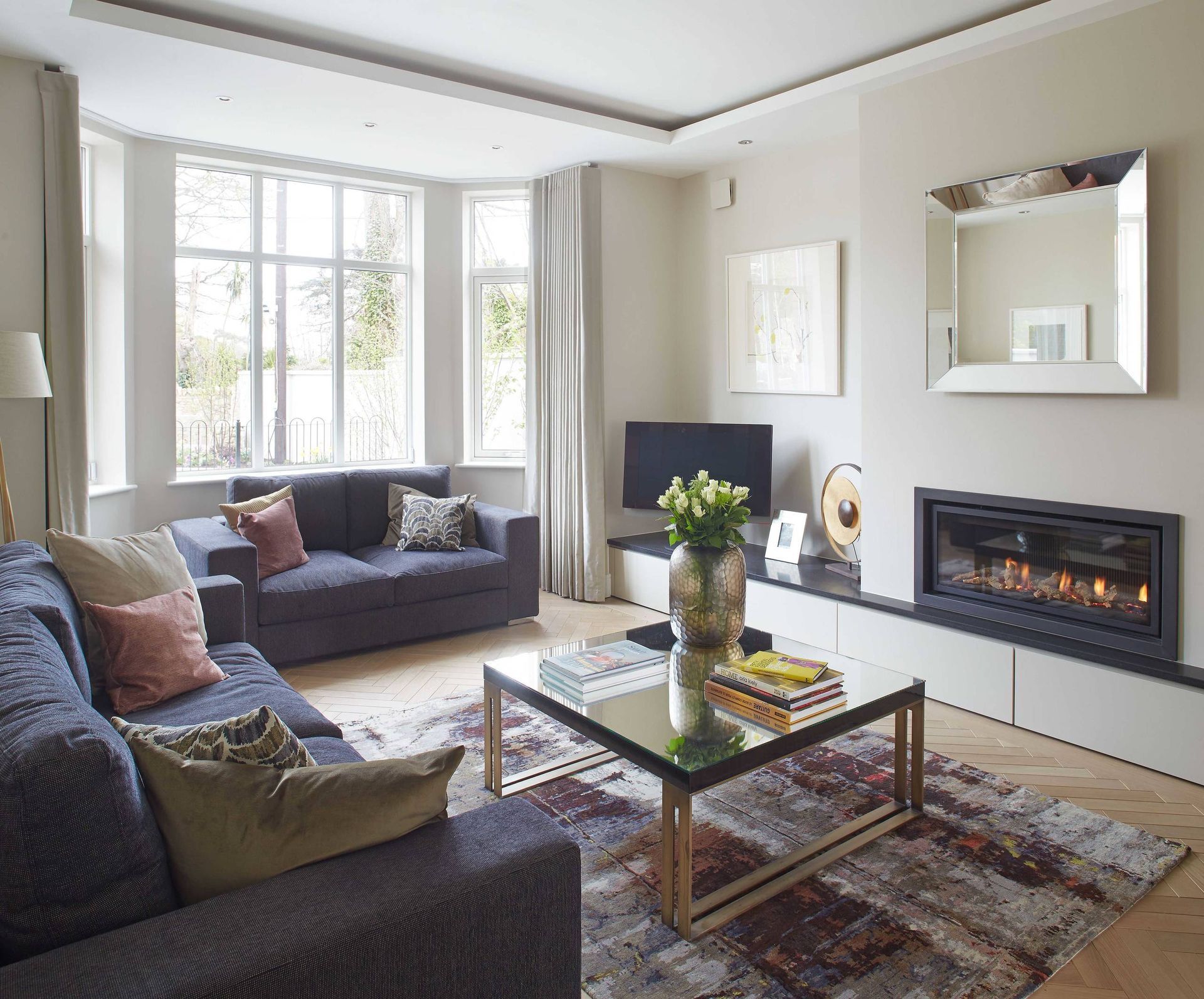A living room with a blue couch , yellow chairs , and a flat screen tv.