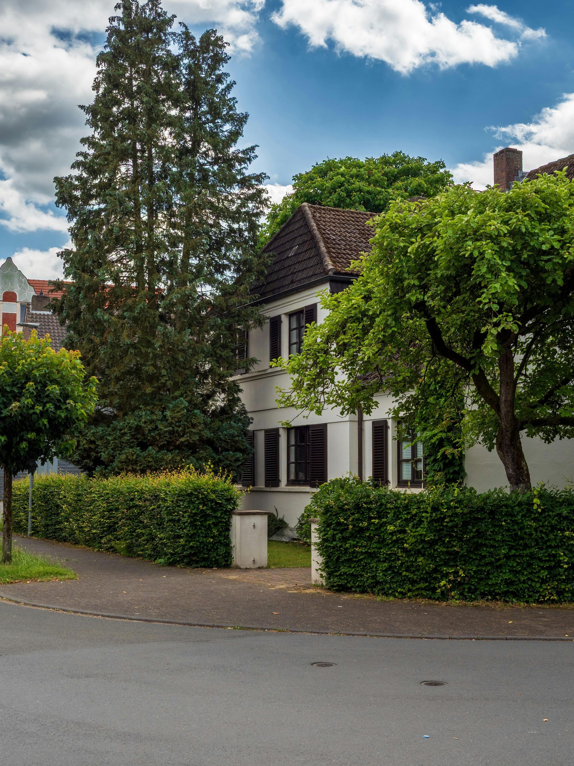 A white house is surrounded by trees and bushes