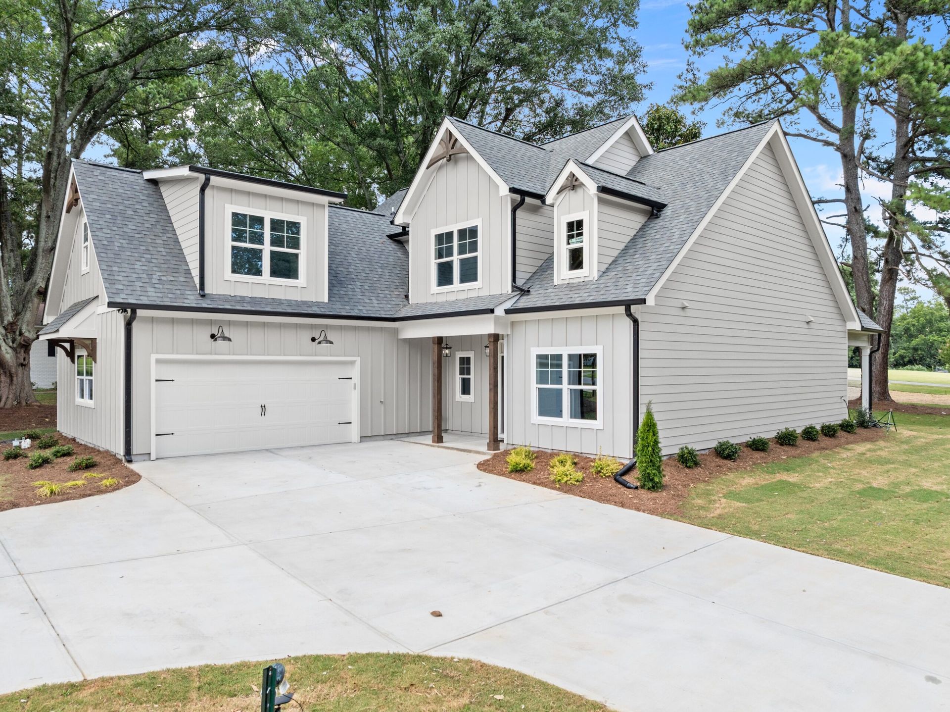 Gray Craftsman-style house with dormers, attached garage, and concrete driveway.
