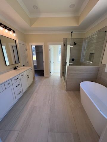 Spacious bathroom with white cabinets, large shower, freestanding tub, and neutral-colored tile flooring.
