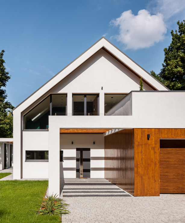 Modern white house with a gabled roof, wooden garage door, and a paved entrance.