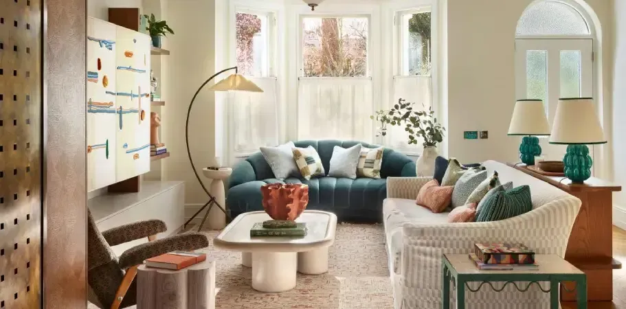 Living room with blue velvet sofa, wicker sofa, and art. Neutral colors with colorful accents.