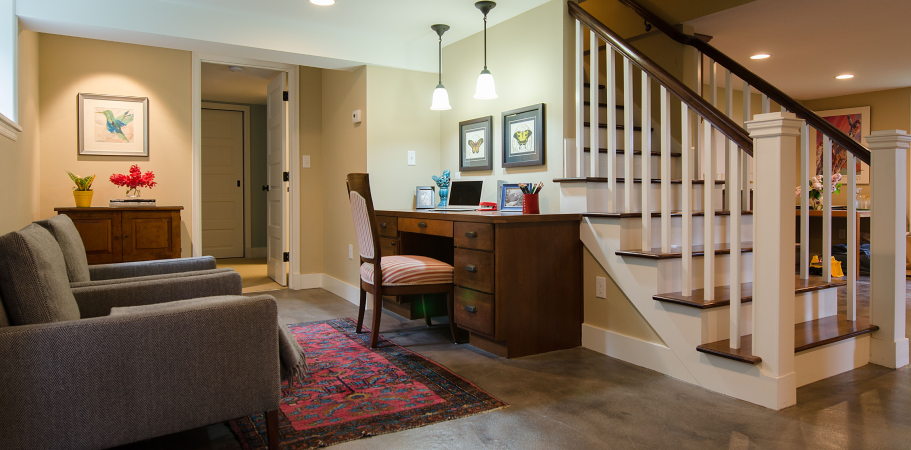 Cozy basement with stairs, desk, and seating area in neutral tones.