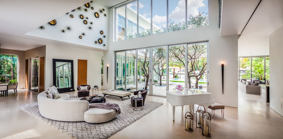 Modern, bright living room with large windows, white walls, and a white piano.
