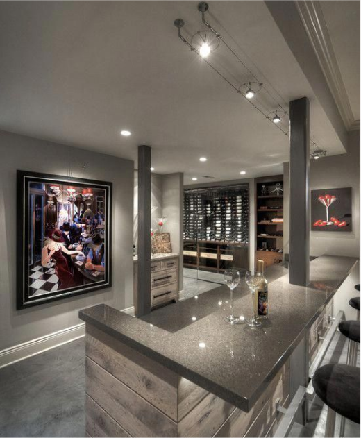 Wine bar in basement with granite countertop, artwork, wine storage, and track lighting.
