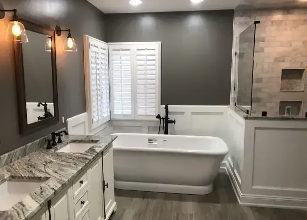 Bathroom with white vanity, gray walls, freestanding tub, and shower with white tile.
