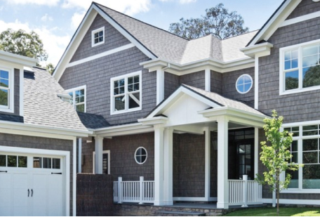 Gray-shingled house with white trim, porch, and garage. Features windows, a circular window, and a dark roof.