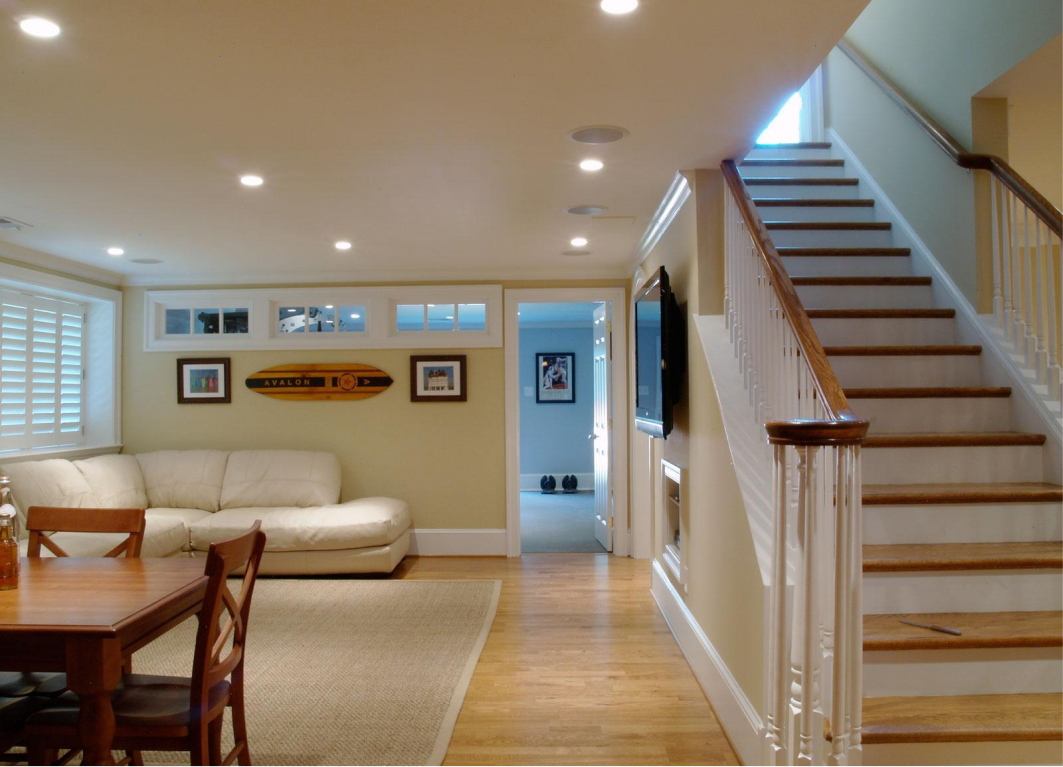 Basement living space with couch, wooden table, and staircase leading upwards.