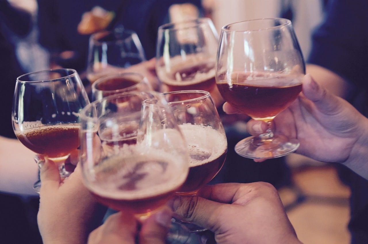 Hands clinking glasses of amber beer, a toast among friends.