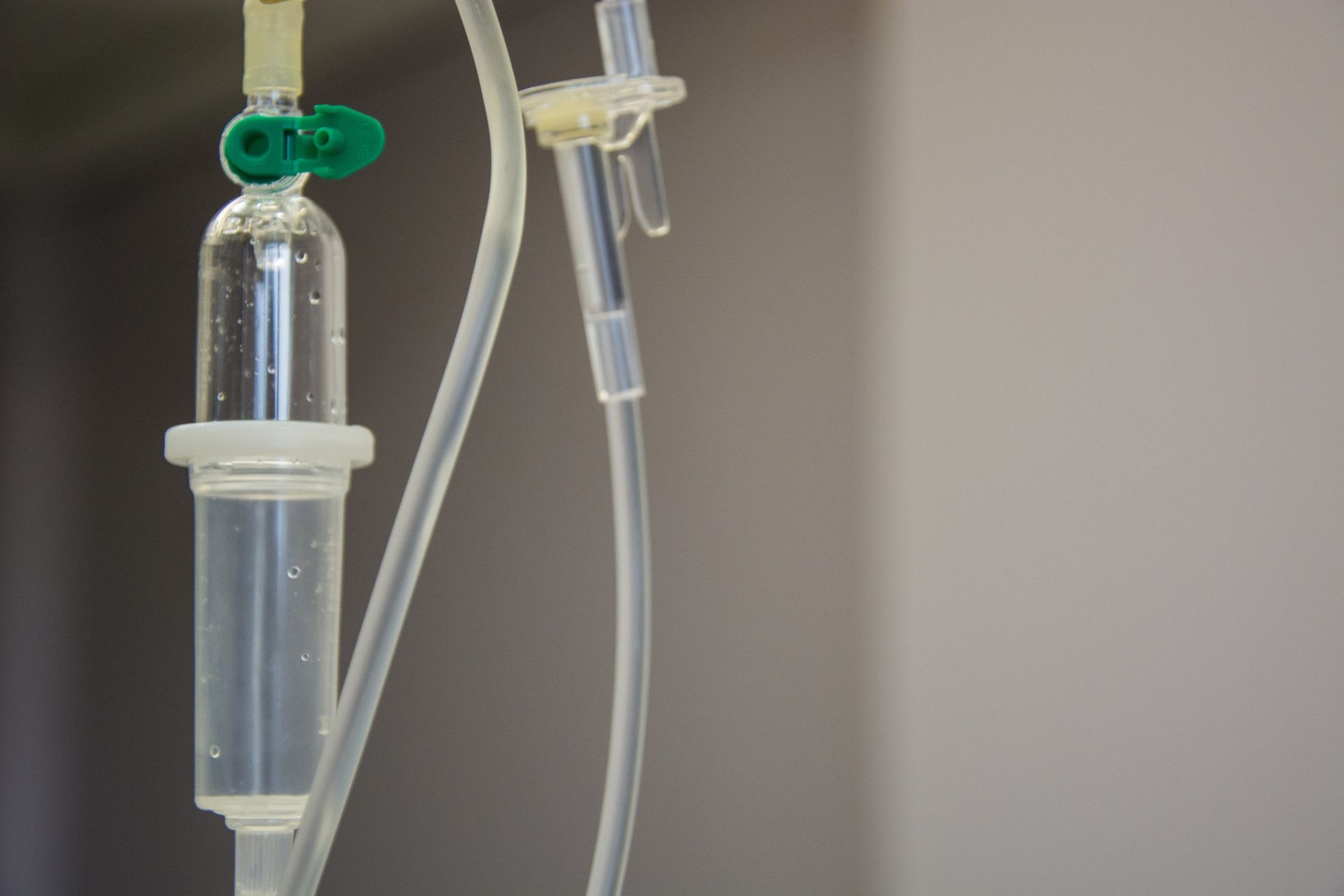 IV drip with clear liquid and tubing against a plain background.