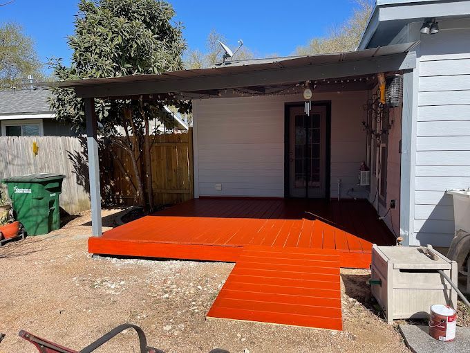 A red deck is being painted in front of a white house.