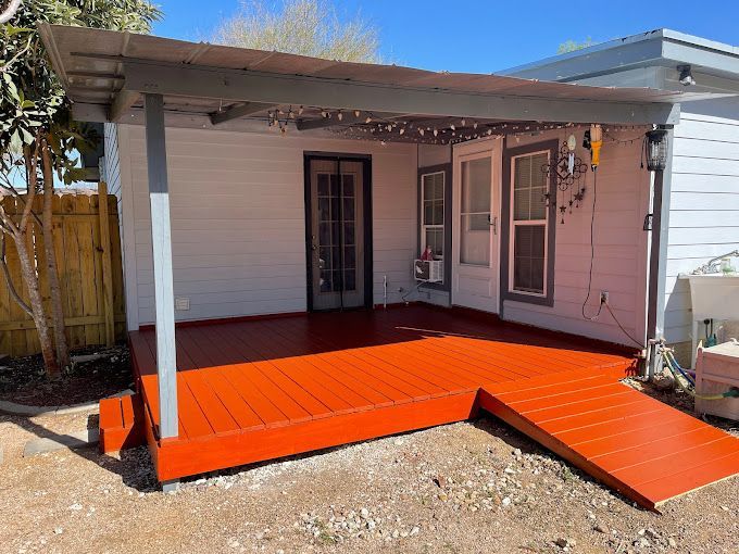 A small house with a covered porch and an orange deck.