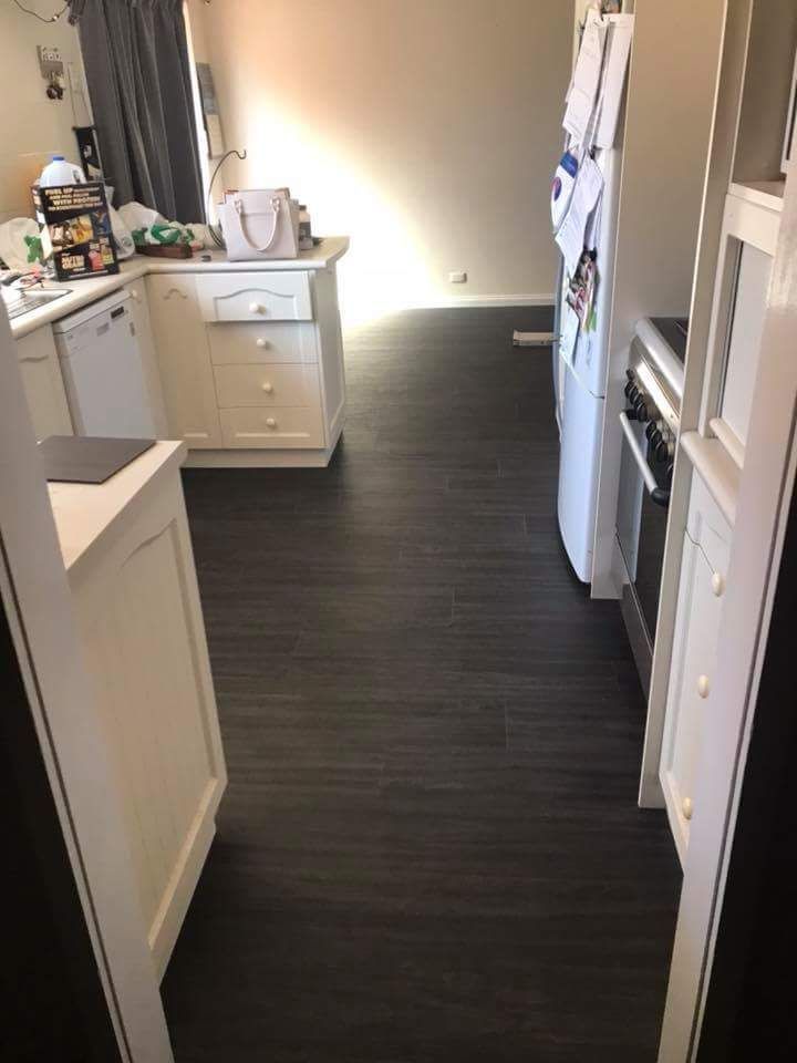 A Kitchen With A Black Floor And White Cabinets And Appliances — Flooring in Queanbeyan, NSW