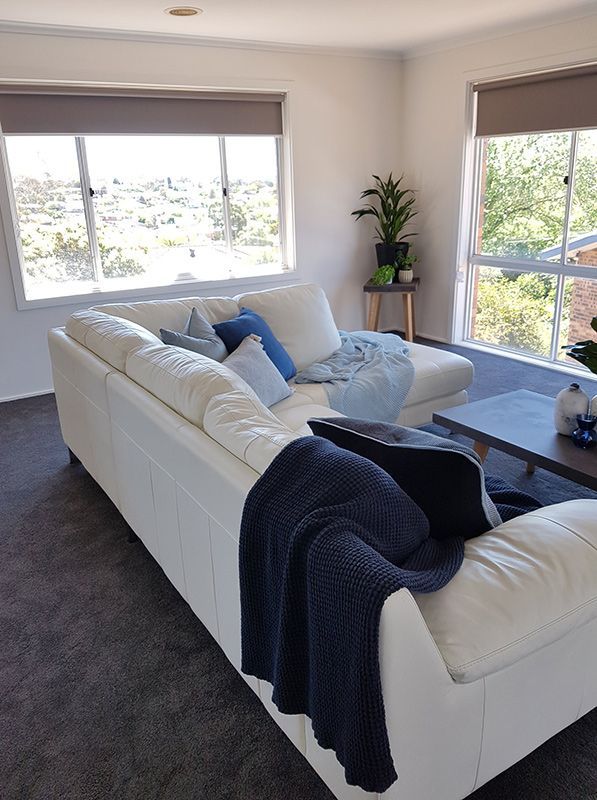 A Living Room With A White Couch, Black Carpet, And A Blue Blanket On It — Carpets & Flooring in Queanbeyan, NSW