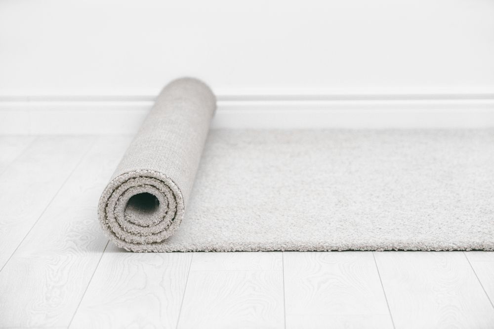 Rolled Grey Carpet on a White Floor Next to a Wall — Queanbeyan Carpets in Queanbeyan, NSW
