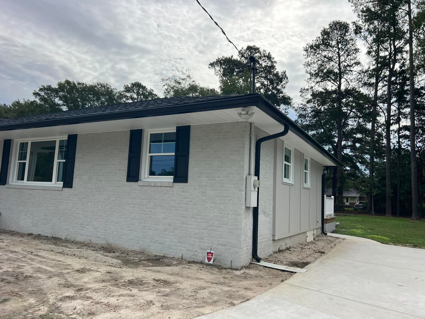 A white brick house with black shutters and a driveway