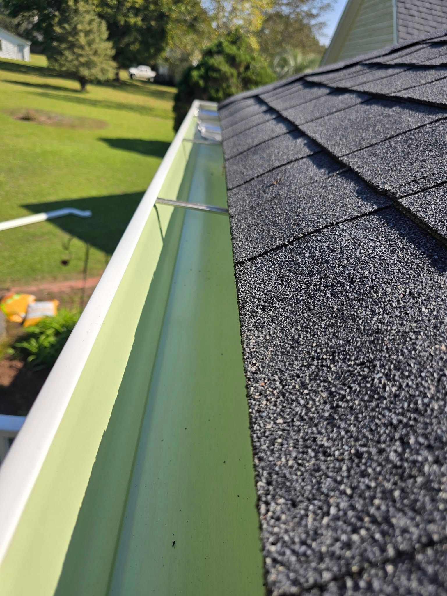 A green gutter is attached to a black roof.