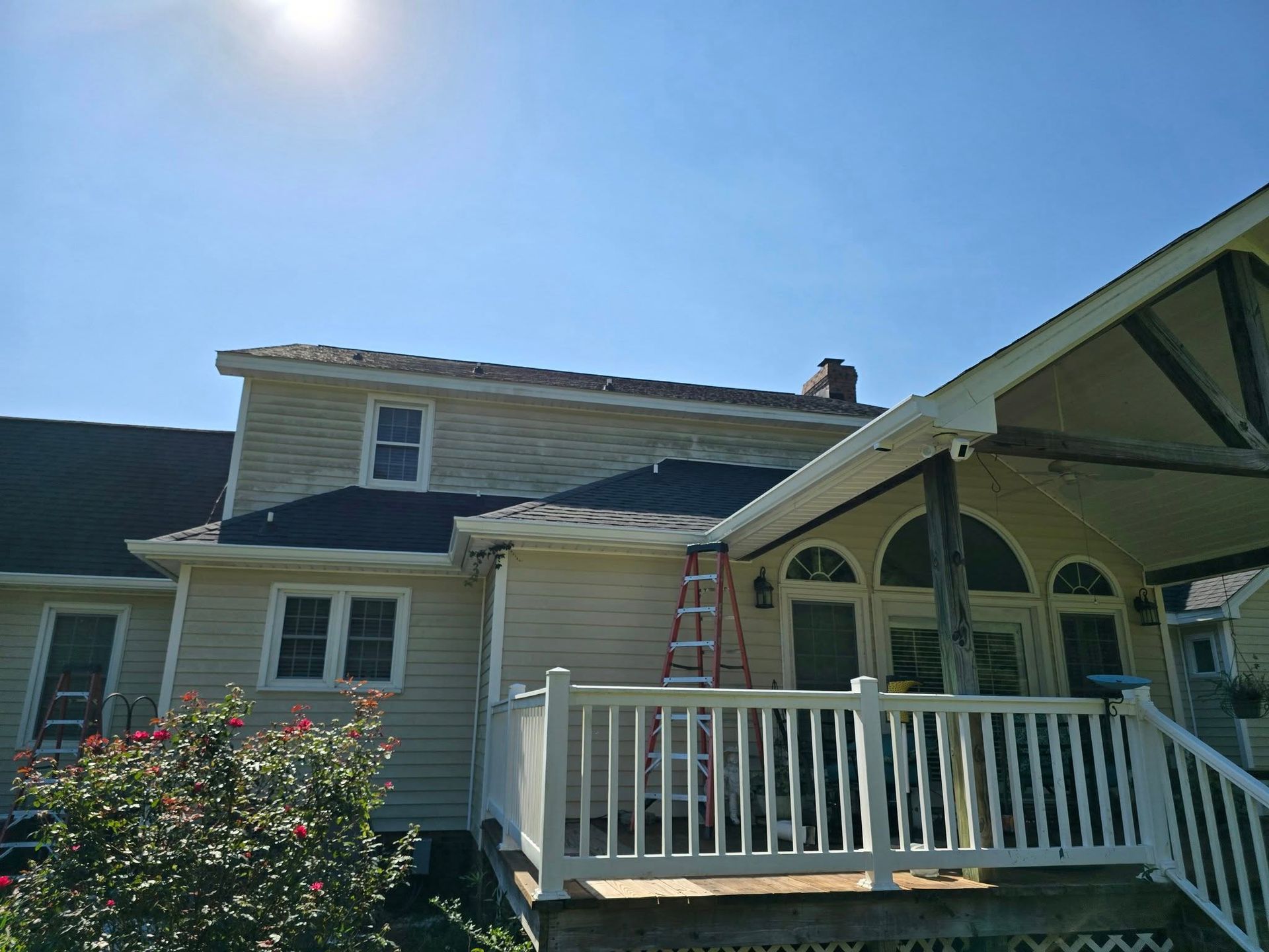A house with a porch and a ladder on the roof.