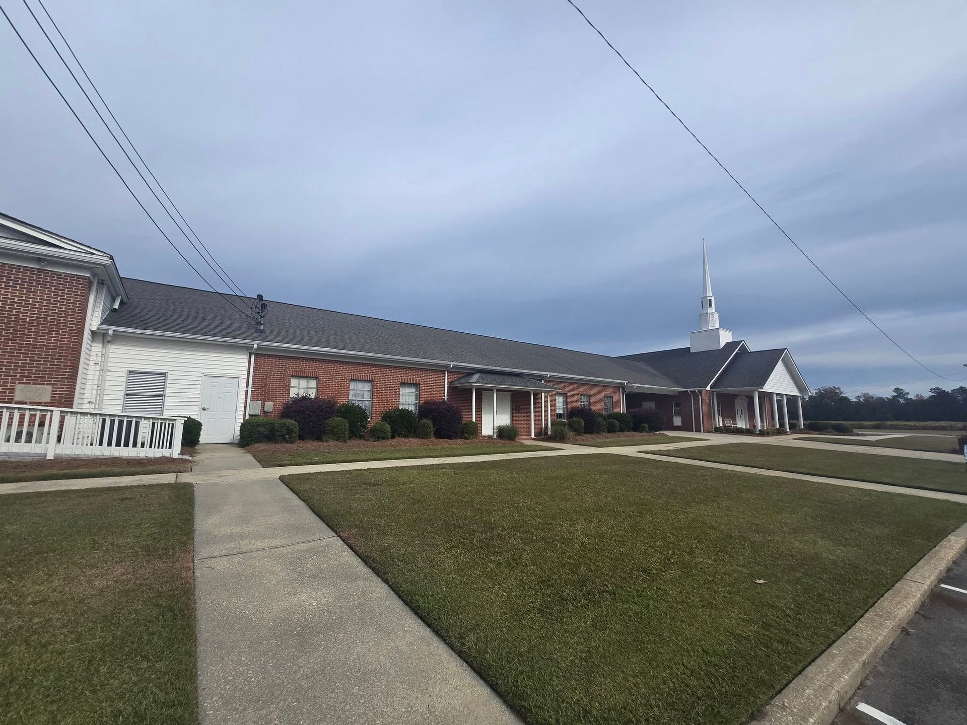 A church with a steeple and a walkway in front of it.