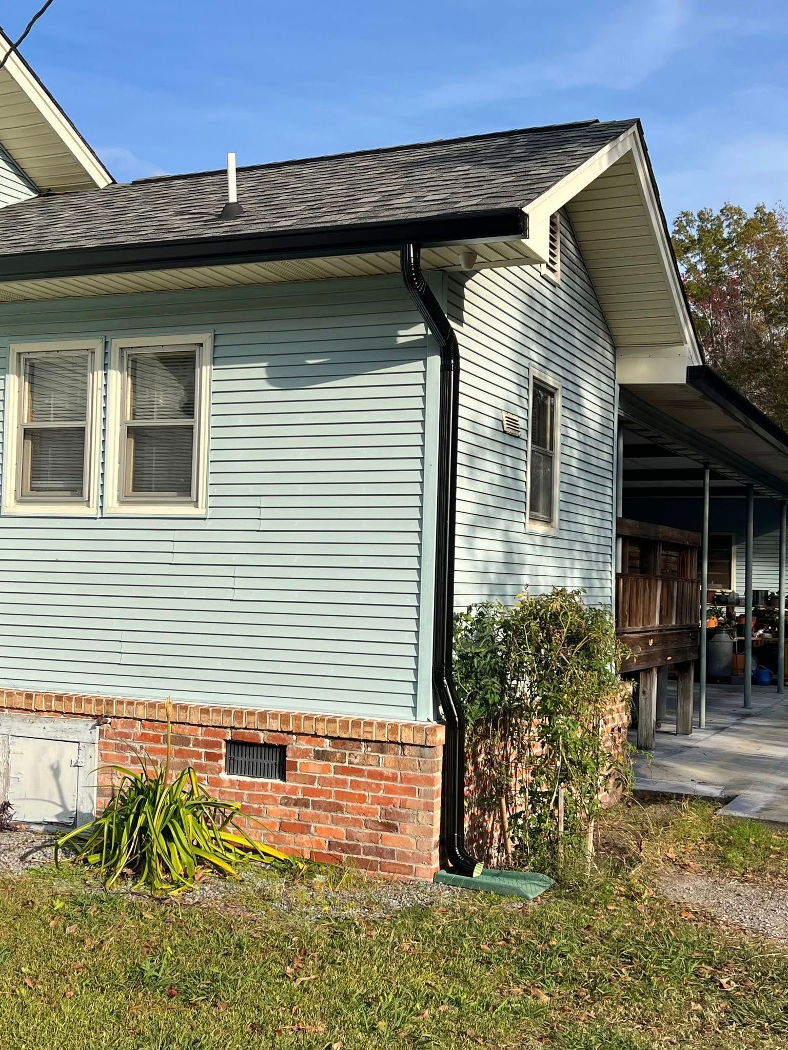 A small blue house with a brick foundation and a porch.