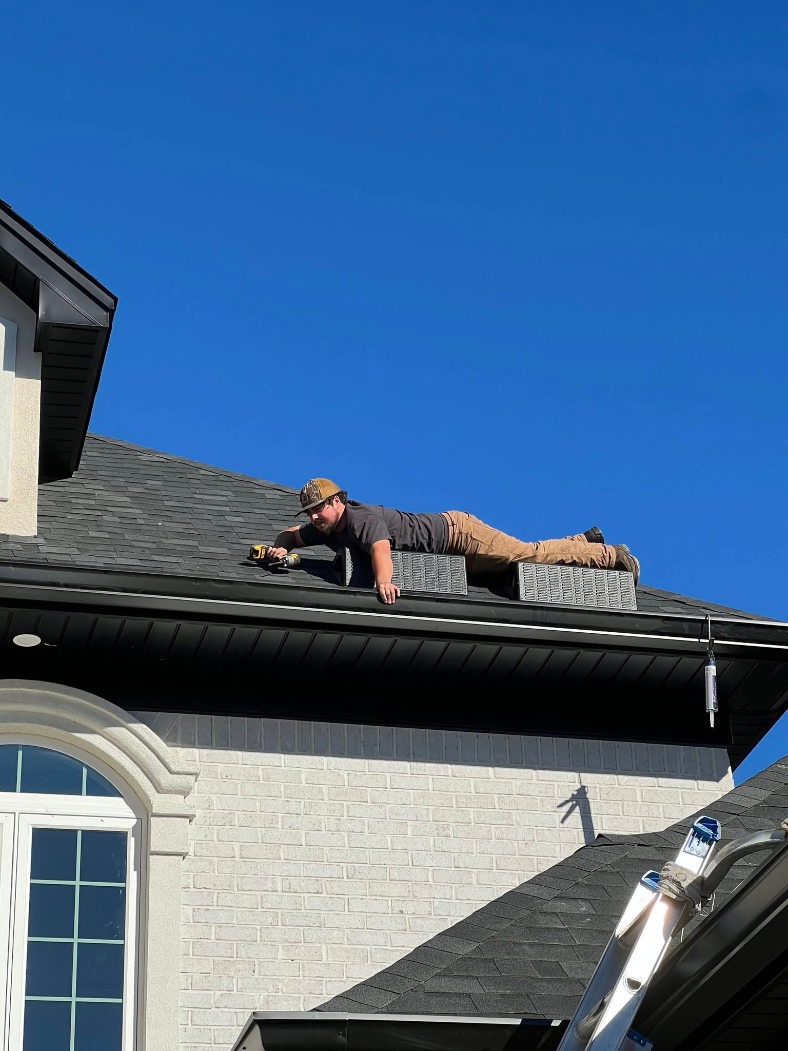 A man is laying on the roof of a house