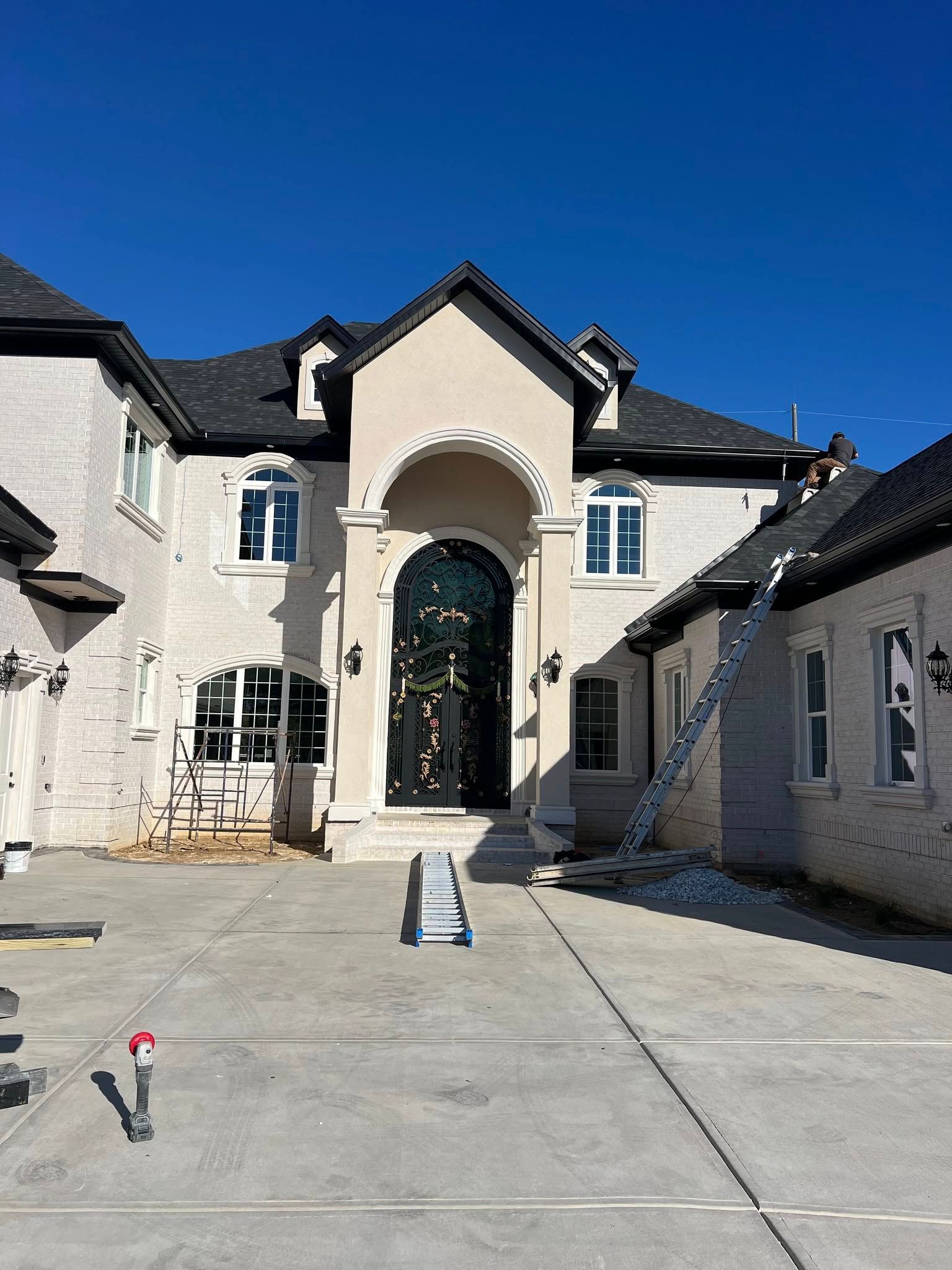 A large white house with a black roof is being painted.