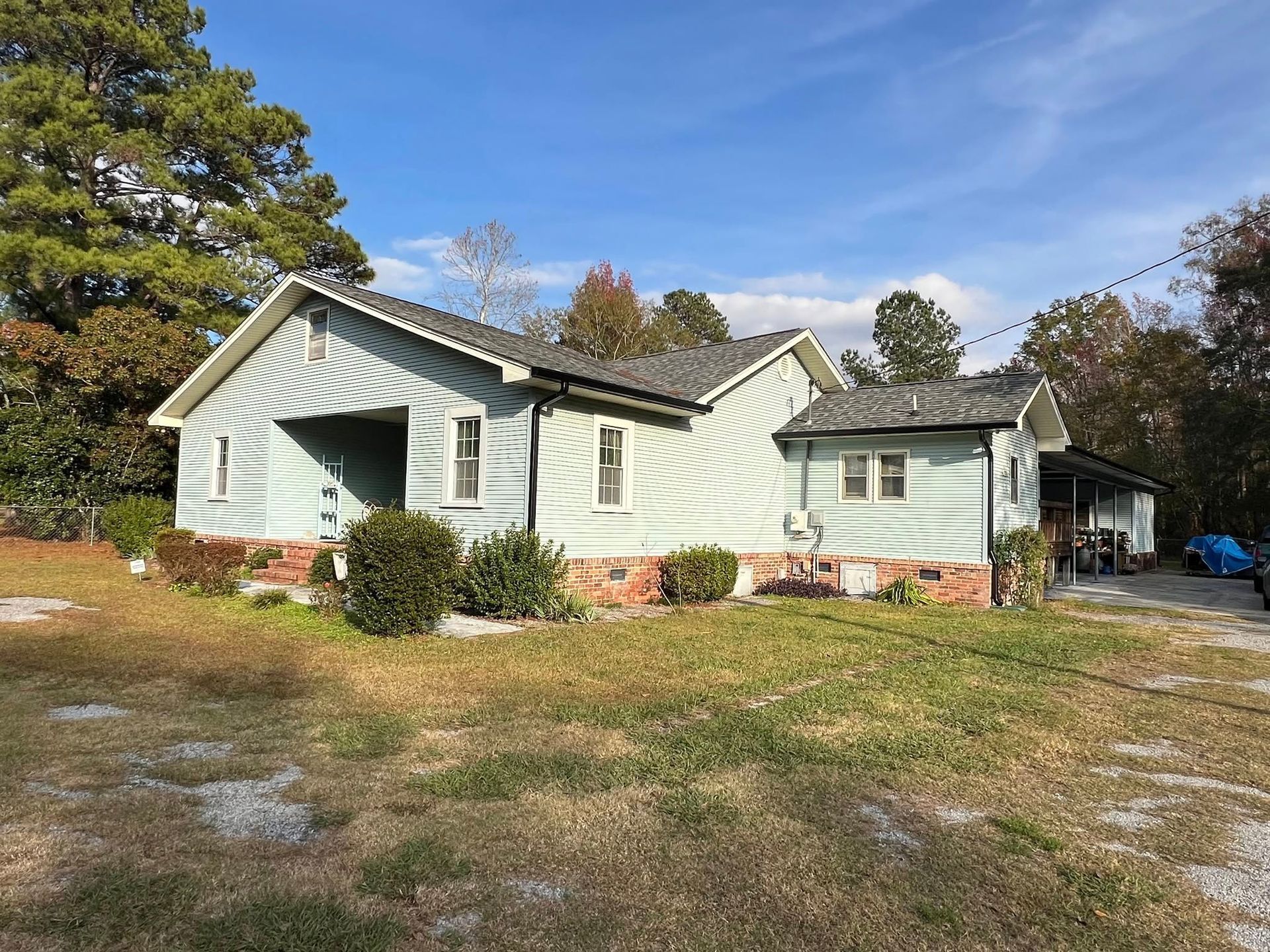 A small house with a gray roof is sitting in the middle of a grassy field.
