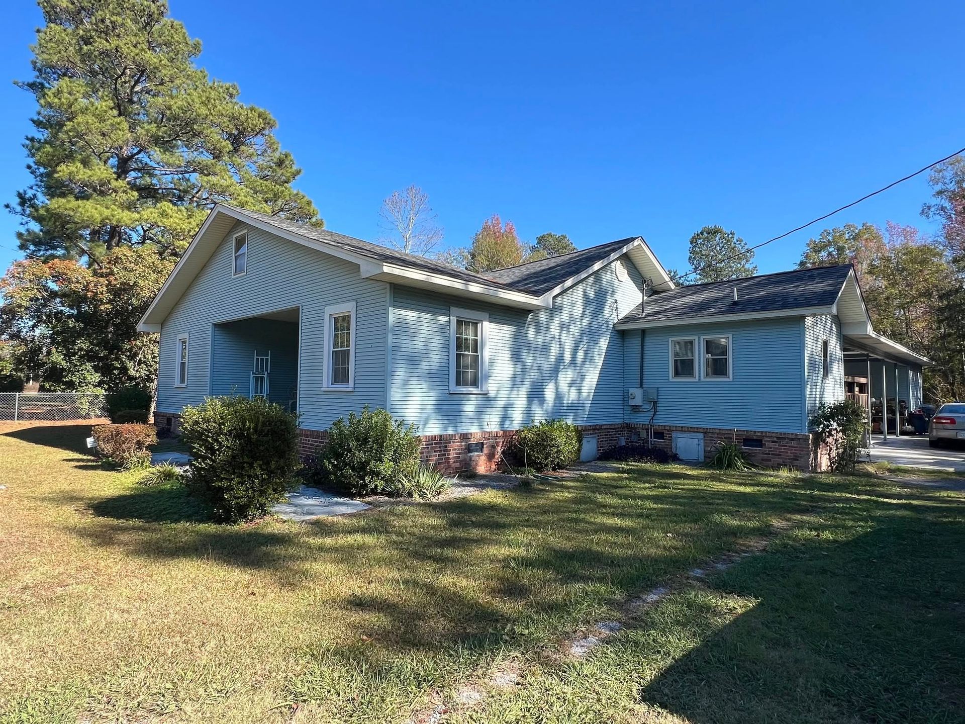 A blue house with a car parked in front of it on a sunny day.