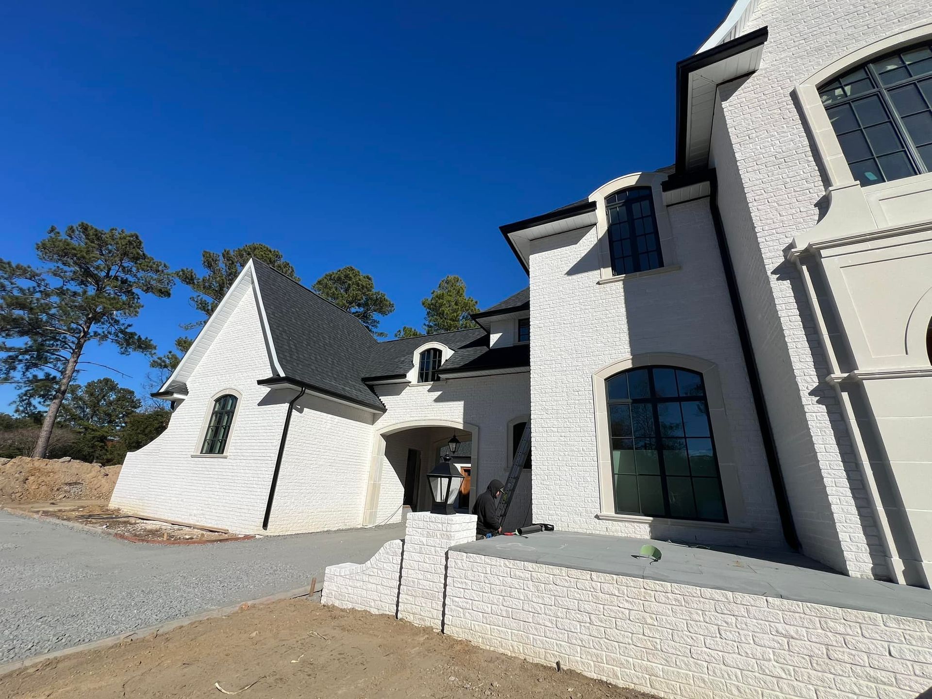 A large white house with a black roof is being built.