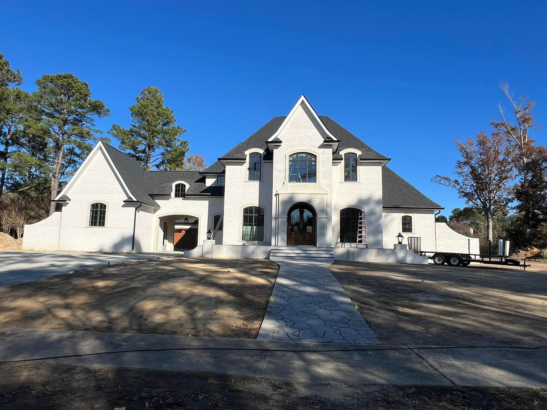 A large white house with a black roof is being built.